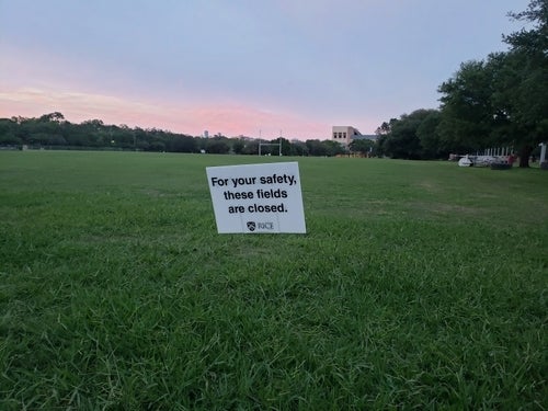 A field on Rice campus with a sign featuring the wording "For your safety, these fields are closed."