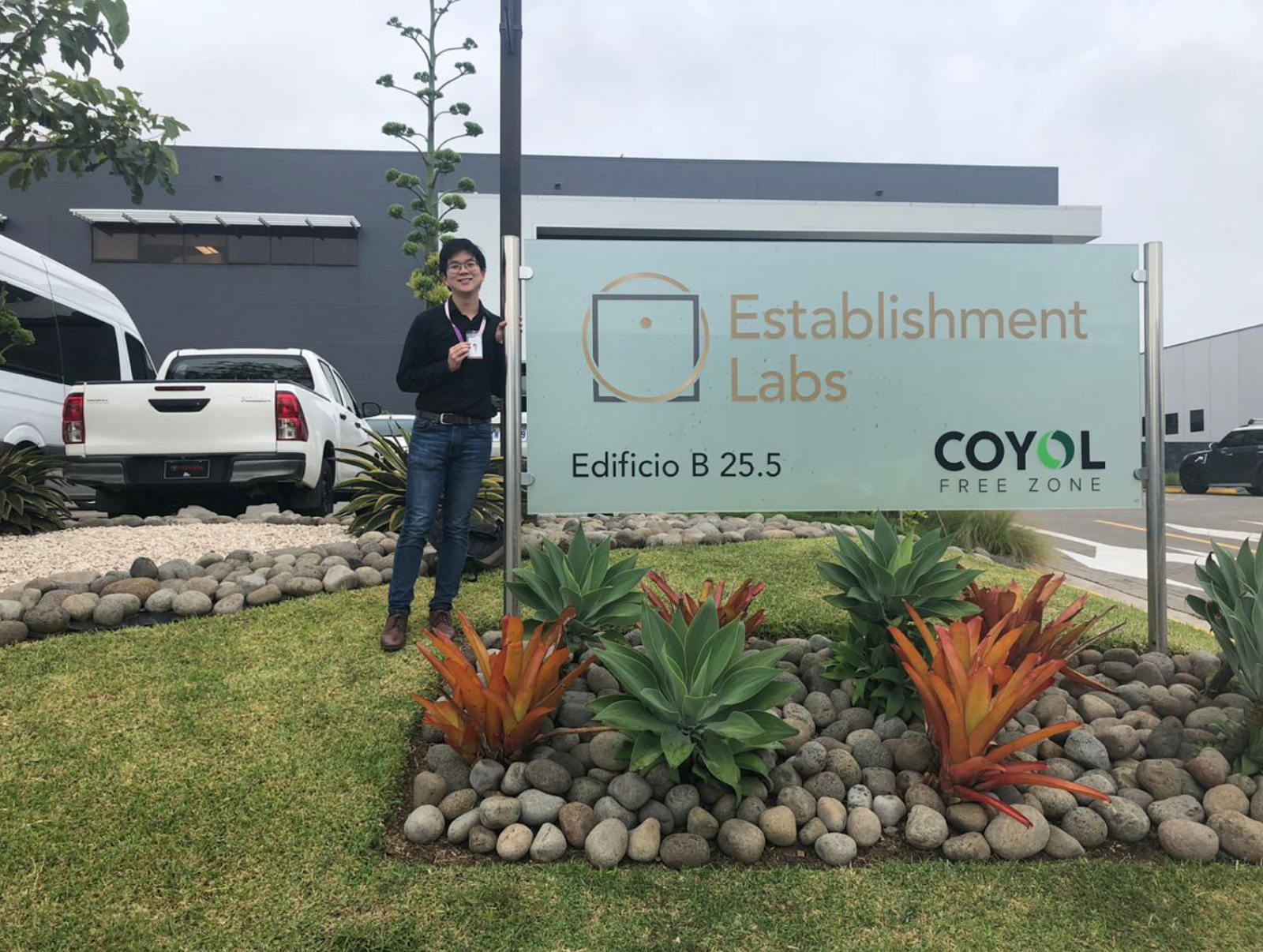 Erik Wu stands in front of the sign for Establishment Labs in Costa Rica.