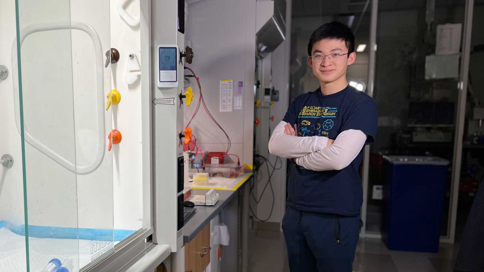 Ryan Wang with arms crossed standing in lab