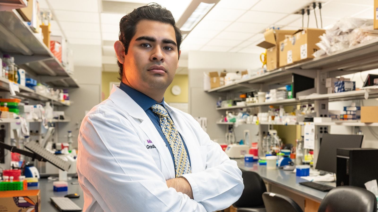 Mario Escobar in a lab dressed in a white lab coat
