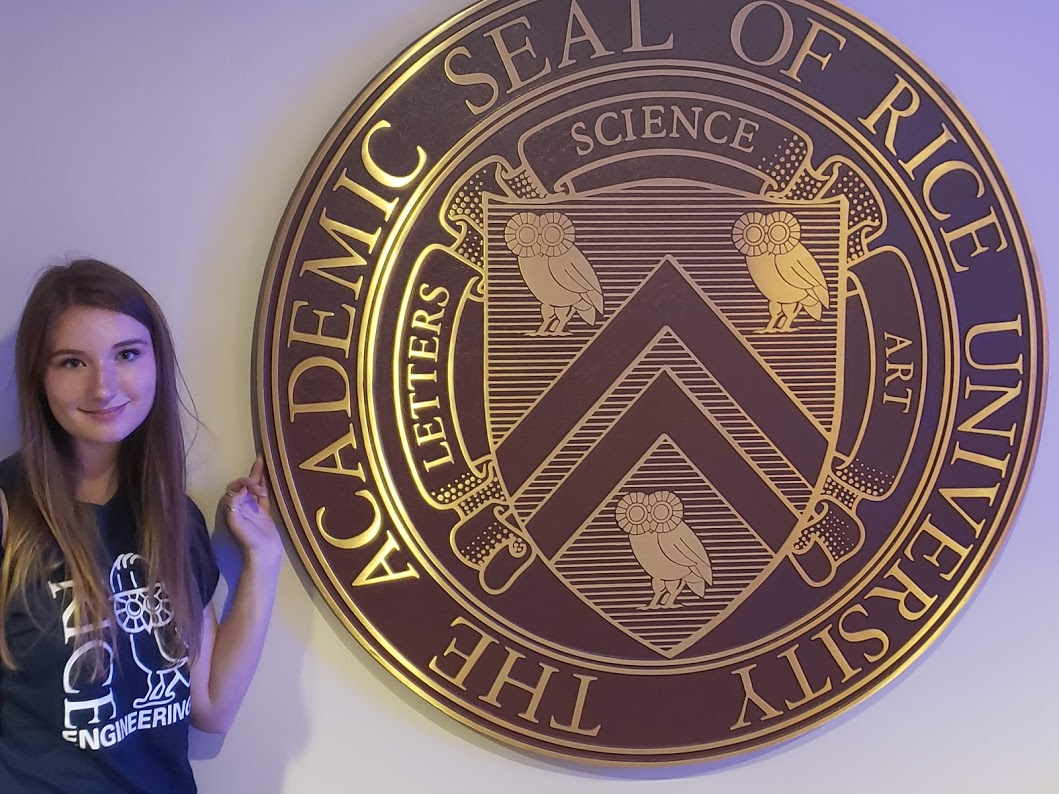Genevieve Wahlert stands in front of the Rice University academic seal.