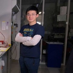 Ryan Wang with arms crossed standing in lab